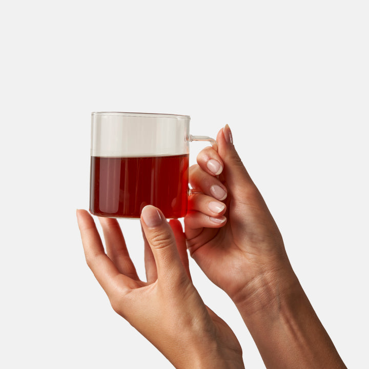 A hand holding a brewed cup of Big Heart Chai